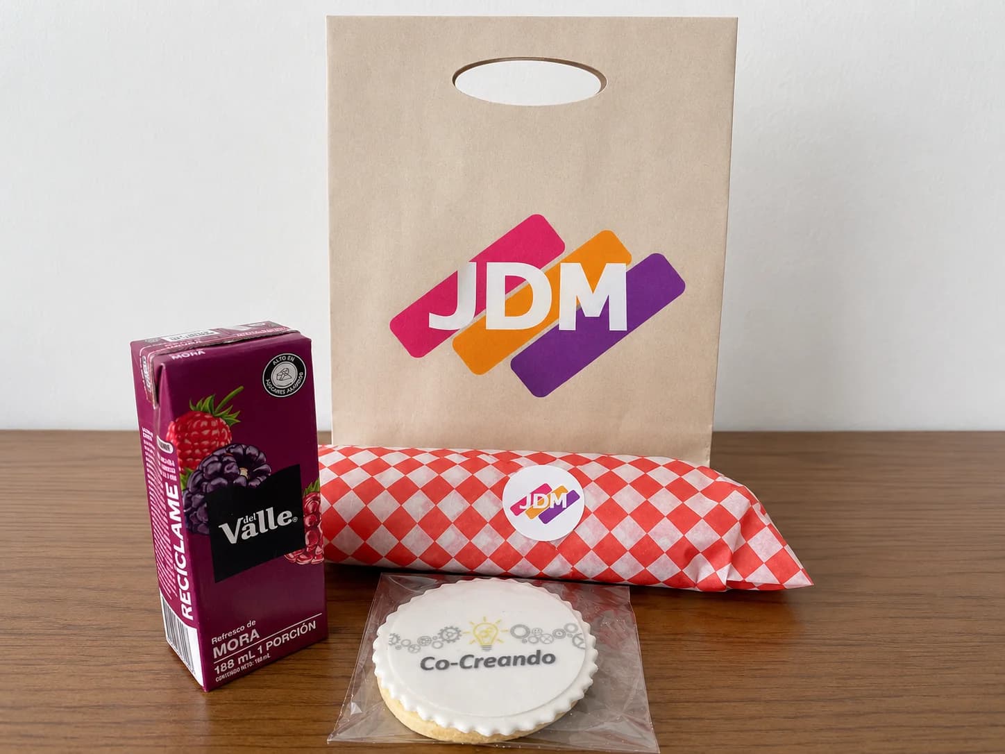 Bolsa de JDM junto a un refrigerio, una bebida y una galleta personalizada